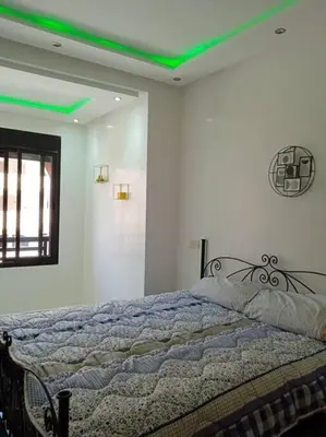 a bedroom with a bed with a green ceiling at Appart Premium Village Marrakech in Marrakech