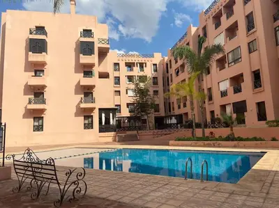 a swimming pool with a bench next to a building at Appart Premium Village Marrakech in Marrakech