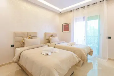 two beds in a white room with a window at Luxury Odyssey - Marrakech Centre in Marrakech