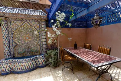 a table and chairs in a room with a blue and white wall at Appartement Guéliz Centre Marrakech in Marrakech