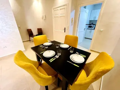 a dining room table with yellow chairs and a black table at Marrakech 2 Bedroom Family Apartment in Marrakech