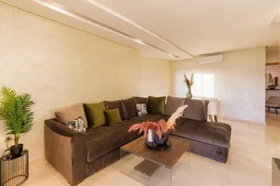 a living room with a brown couch and a table at Appart View Pool - 3 Rooms - Optical Fiber in Marrakech
