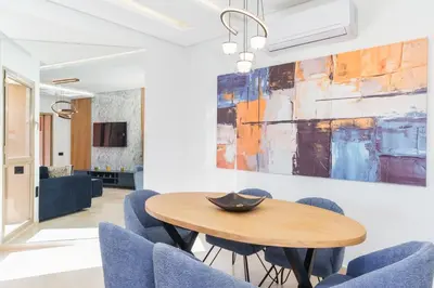 a dining room with a wooden table and blue chairs at Luxueux appartement prestigia golf/vue piscine in Marrakech