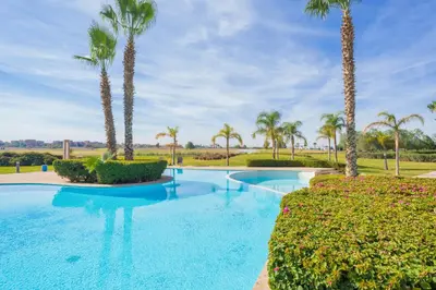a swimming pool with palm trees and bushes at Green Side Golf 3 B.R Apartment in Marrakech