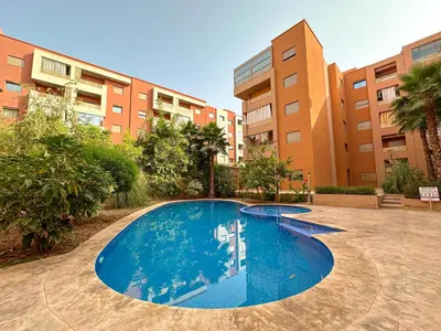 a large blue swimming pool in front of a building at Cozy apartment pool marrakech morocco in Marrakech