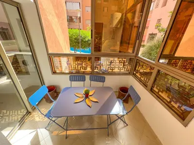 a table and chairs in a room with windows at Cozy apartment pool marrakech morocco in Marrakech