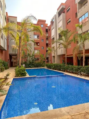 a large blue swimming pool in front of a building at Cozy apartment pool marrakech morocco in Marrakech