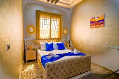 a bedroom with a bed with blue sheets and a window at The Skyline Stay in Marrakech