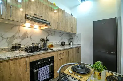 a kitchen with wooden cabinets and a black refrigerator at The Skyline Stay in Marrakech