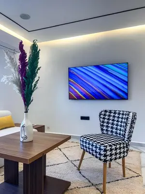 a living room with a table and a chair and a television at Marrakech Apartments in Marrakech