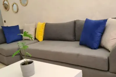 a living room with a couch with colorful pillows at Appartement 2 chambres vue Piscine à Guèliz en face la gare de train marrakech in Marrakech