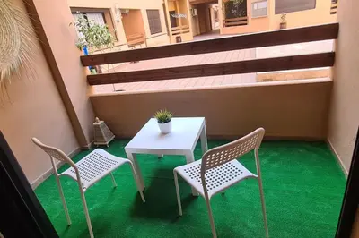 a table and chairs on a balcony with green flooring at Appartement 2 chambres vue Piscine à Guèliz en face la gare de train marrakech in Marrakech