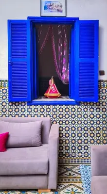 a living room with a blue window and a couch at Riad Sultana - 10 min à pied de Jemaa El Fna in Marrakech