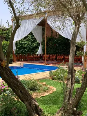 a backyard with a pool and a white canopy at La villa Berbère - Famille uniquement in Marrakech