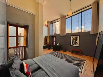 a living room with a bed and large windows at Riyad Lion Rouge in Marrakech