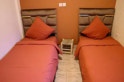 two beds in a room with orange pillows at Appartement MSholidays Gazelle Marrakech in Marrakech