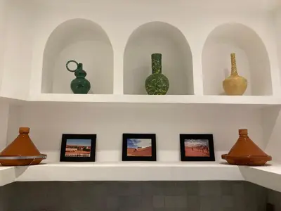 a shelf with vases on it with framed pictures at Riad Bella Kasbah in Marrakech