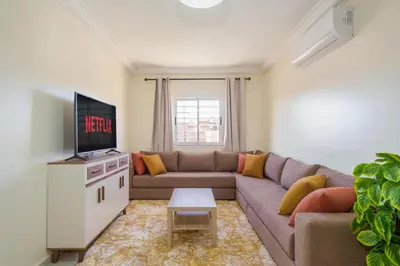 a living room with a couch and a tv at Appartement 2 chambres Aéroport in Marrakech