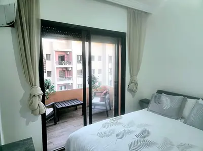 a bedroom with a bed and a view of a balcony at appartement cosy plein centre in Marrakech
