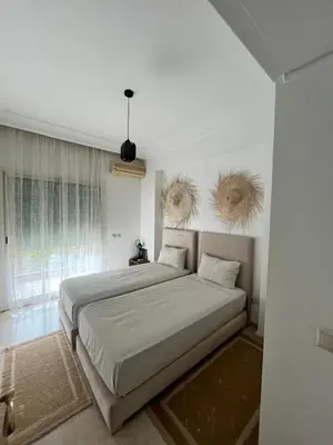 a white bedroom with a large bed and a window at Appartement piscine in Marrakech