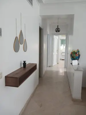 a living room with white walls and a table on the wall at Appartement piscine in Marrakech
