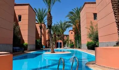 a swimming pool with palm trees in a resort at Riad Sun and Swim Marrakech in Marrakech