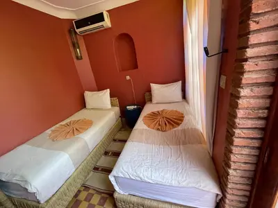 two beds in a small room with orange walls at Riad Lwalidin in Marrakech