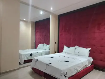 a bedroom with two beds and a red wall at résidence assafa central H26 in Marrakech