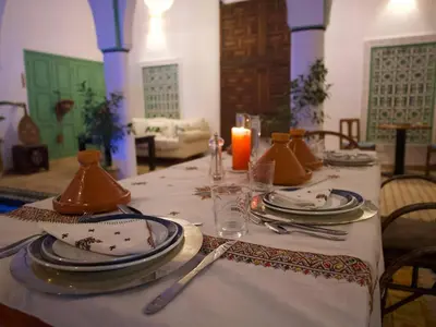 a table with plates and utensils and a candle at Riad Ocallaghan in Marrakech