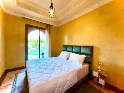 a bedroom with a large bed in a yellow wall at Les jardins de la palmeraie résidence touristique in Marrakech