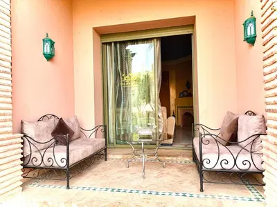 two chairs and a glass table on a patio at Les jardins de la palmeraie résidence touristique in Marrakech
