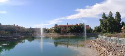 a pond with a fountain in front of a building at Les jardins de la palmeraie résidence touristique in Marrakech
