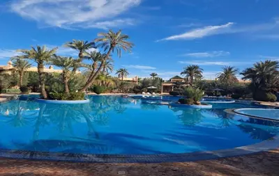 a large swimming pool with palm trees in a resort at Les jardins de la palmeraie résidence touristique in Marrakech