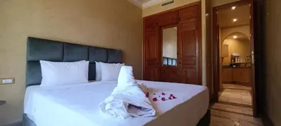 a bedroom with a white bed with a baby on it at Les jardins de la palmeraie résidence touristique in Marrakech