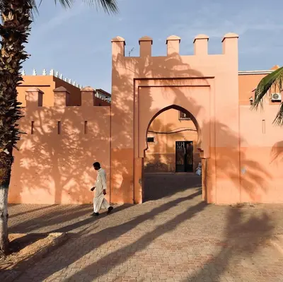 a man walking in front of a building at Riad El Khaeir - Piscine, Hamam & Spa in Marrakech