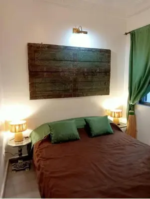 a bedroom with a large bed with two green pillows at Riad EL BADI in Marrakech