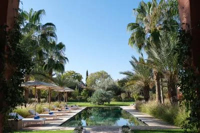a pool with lounge chairs and palm trees at Villa JENAMAN in Marrakech