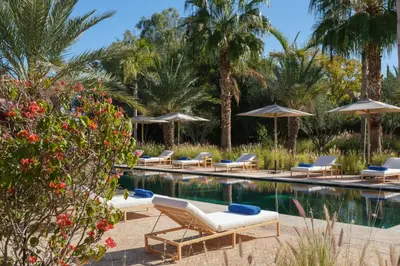 a resort pool with lounge chairs and umbrellas at Villa JENAMAN in Marrakech