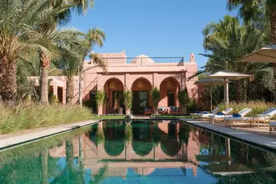 a swimming pool in front of a house with palm trees at Villa JENAMAN in Marrakech