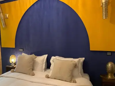a bedroom with a bed with a blue and yellow wall at Riad SunSet Marrakech in Marrakech