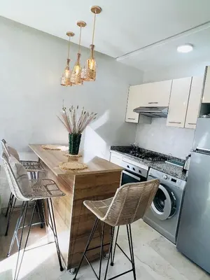 a kitchen with a table and chairs and a refrigerator at Nouvel appartement de luxe Pearl garden in Marrakech