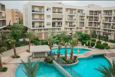 an apartment complex with a pool and palm trees at Nouvel appartement de luxe Pearl garden in Marrakech