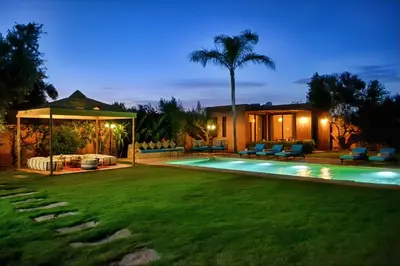 a backyard with a swimming pool at night at Domaine Homa Marrakech in Marrakech