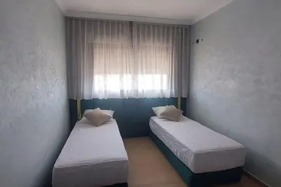 two beds in a small room with a window at Luxury city center apartment with swimming pool in Marrakech