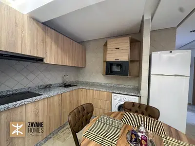 a kitchen with a table and a white refrigerator at Premium Hivernage Amazigh 2BR Flat - Zayane Homes in Marrakech