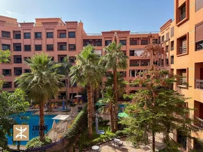 a hotel with palm trees in front of a building at Premium Hivernage Amazigh 2BR Flat - Zayane Homes in Marrakech