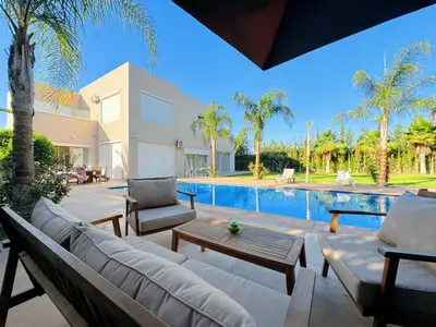 a patio with a couch and chairs next to a swimming pool at Villa Marrakech, 15 min from center, Disco, Hammam in Marrakech