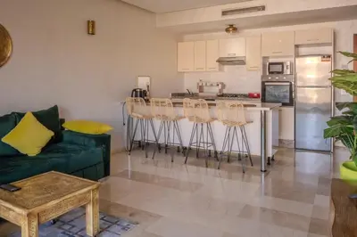 a living room with a couch and a kitchen at Oasis urbaine - Pearl Garden luxe et confort in Marrakech
