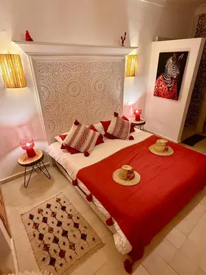 a bedroom with a large bed with a red blanket at Riad Marssa, Privé Zen avec belle piscine dans la Médina in Marrakech