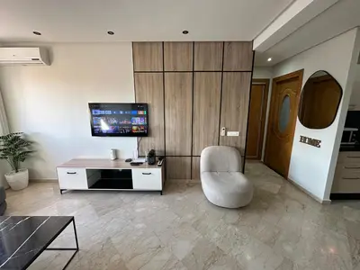 a living room with a chair and a tv at Appartement chic et cosy en plein centre de Gueliz in Marrakech
